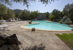 a large swimming pool in a yard with rocks at Modern Villa in Olbia with Shared Pool - 45 sqm in Porto Rotondo