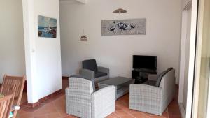 a living room with chairs and a table and a television at Maison charmante à Gros-Morne + jardin in Gros-Morne