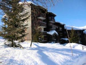un bâtiment dans la neige avec un arbre devant lui dans l'établissement Appartement de 2 chambres avec terrasse amenagee a La plagne, à La Plagne