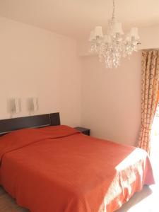 Schlafzimmer mit einem roten Bett und einem Kronleuchter in der Unterkunft Appartement d'une chambre a Antibes a 250 m de la plage avec jardin clos et wifi in Antibes
