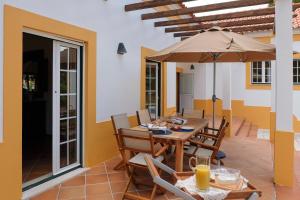 ein Esszimmer mit einem Tisch und einem Sonnenschirm in der Unterkunft 4 bedrooms villa with private pool enclosed garden and wifi at Comporta in Montalvo