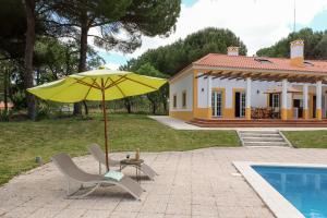 un parasol jaune, une chaise, une table et une maison dans l'établissement 4 bedrooms villa with private pool enclosed garden and wifi at Comporta, à Montalvo
