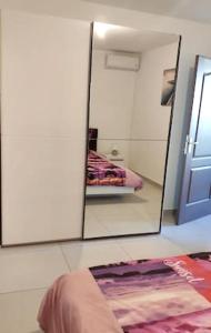 espejo en la pared en una habitación con cama en Appartement charmant à Saint Pierre 44 m² avec jardin clôturé, en Saint-Pierre