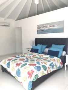 een slaapkamer met een groot bed met blauwe kussens bij Villa de 2 chambres avec vue sur la mer piscine privee et jardin clos a Le Moule a 1 km de la plage in Le Moule