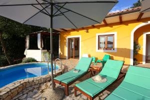 a patio with chairs and an umbrella next to a pool at Charming villa with private pool near the sea and garden in Ripenda Kras