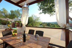 a wooden table with a bottle of wine on a patio at Charming villa with private pool near the sea and garden in Ripenda Kras