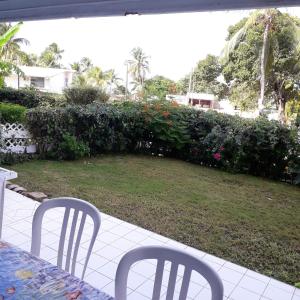 a patio with two chairs and a table and a garden at Appartement confortable avec vue sur la mer - 88 m² à Le Moule in Le Moule