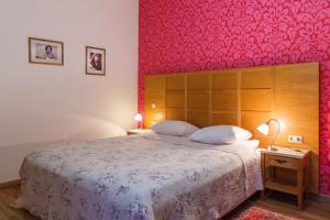 a bedroom with a large bed with a pink wall at Hotel Vila Diemedis in Palanga