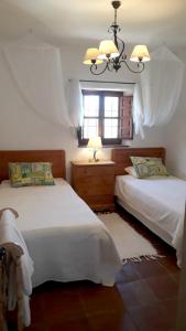 1 dormitorio con 2 camas, ventana y lámpara de araña en 3 bedrooms house with private pool enclosed garden and wifi at Los Romanes, en Benamargosa