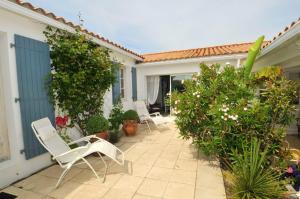 a patio with white chairs and plants on a house at Maison accueillante avec jardin, Sainte-Marie-de-Ré in Sainte-Marie-de-Ré