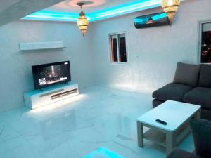 马拉喀什Charming Triplex in Annakhil, Marrakech with Shared Pool的带电视、沙发和桌子的客厅