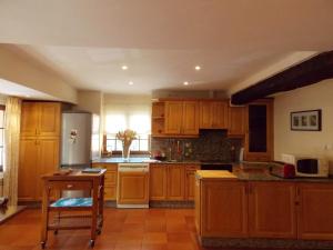 a large kitchen with wooden cabinets and a table at Spacious House in Molinaseca with Mountain View in Molinaseca