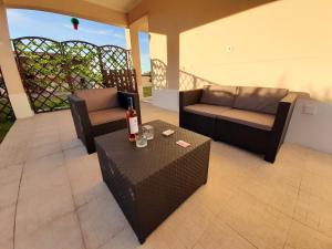 a patio with two couches and a table with a bottle of wine at 4 bedrooms house with private pool and wifi at Aldeia dos Pinheiros in Azeitao