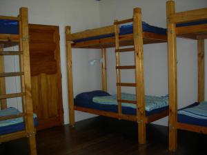 a room with three bunk beds with blue sheets at White Elephant Accomodation in Motueka