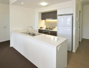 a white kitchen with a sink and a refrigerator at Apartments G60 Gladstone in Gladstone