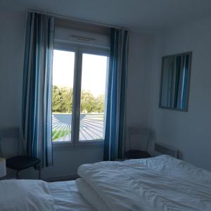 a bedroom with a bed and a large window at Les Pins - 3 pièces - Vue sur piscine - 600m mer - Les Sables d'Olonne in Les Sables-dʼOlonne