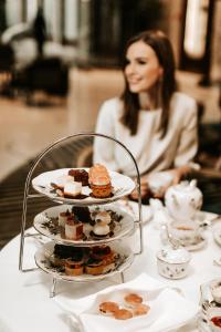 a woman sitting at a table with plates of pastries at Four Seasons Hotel Gresham Palace Budapest in Budapest