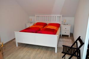 a bedroom with a bed with red and orange sheets at Ferienwohnung Klaus in Dolní Lánov