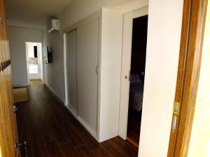 a hallway with white walls and wooden floors and a door at La Cabaña in Guía de Isora