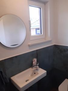 ein Badezimmer mit einem weißen Waschbecken und einem Spiegel in der Unterkunft Tante Käthe in Nordstrand