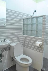 a white bathroom with a toilet and a sink at Aloha Hotel Yogyakarta in Yogyakarta