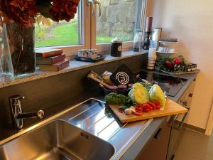 una cocina con fregadero y una tabla de cortar con verduras en Limes Apartment -übernachten am Limes- en Rainau