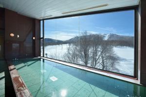 a swimming pool with a view of a snowy mountain at Hotel Grand Phenix Okushiga in Yamanouchi
