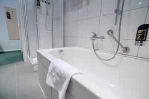 ベルリンにあるホテル ティーアガルテン ベルリンの白いバスルーム(バスタブ、シャワー付)