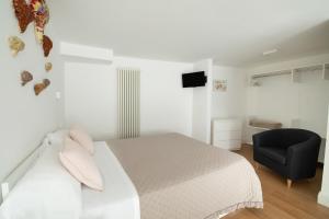 1 dormitorio con 1 cama blanca y 1 silla negra en Palazzo Torriglioni en Ancona