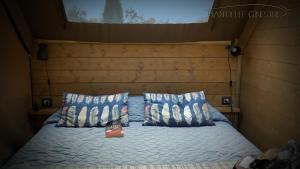 Una cama con dos almohadas y una caja. en Glamping Pian delle Ginestre, en Sassetta