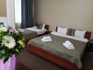 um quarto com duas camas e um vaso de flores em Orange Hotel em Lviv