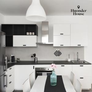 a kitchen with white cabinets and a table with a vase of flowers at Huonder House in Lecco