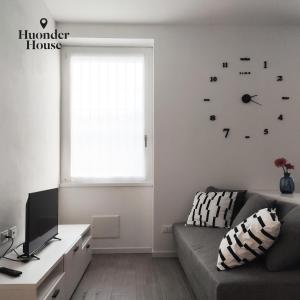 a living room with a couch and a clock on the wall at Huonder House in Lecco
