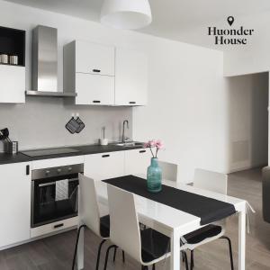 a kitchen with white cabinets and a table and chairs at Huonder House in Lecco