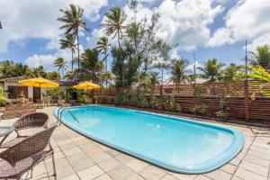 una piscina con sillas y sombrillas en un patio en Pousada Iandê, en Porto de Galinhas