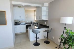 a kitchen with a counter and two stools in it at LICORNA BEACH 51 UMHLANGA BEACHFRONT in Durban