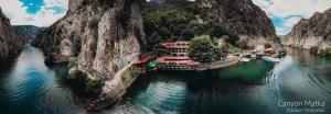 a boat is docked in a river between two mountains at Canyon Matka Hotel in Matka