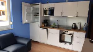 a kitchen with white cabinets and a blue wall at Die kleine Kajüte in Ueckeritz