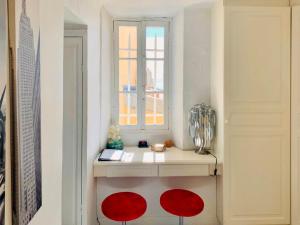 a room with a window and a table with red chairs at Les Remparts Antibes Location in Antibes