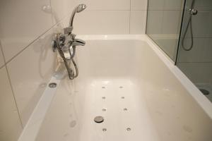 a white bath tub with a shower and a phone at Vakantiewoning Weverijstraat met strandcabine in Domburg +22 photos