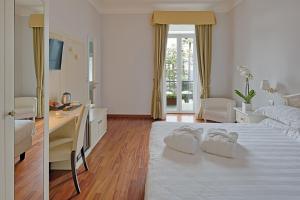 a white bedroom with a desk and a bed at Hotel Paradiso in Sanremo