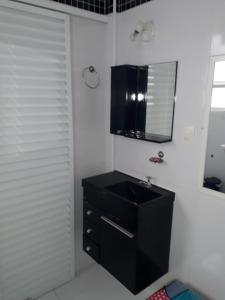 baño con lavabo negro y espejo en Kitnet em Guarujá - Pitangueiras (sem garagem), en Guarujá