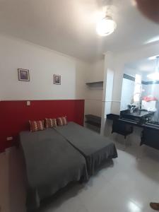1 dormitorio con cama y escritorio. en Kitnet em Guarujá - Pitangueiras (sem garagem), en Guarujá