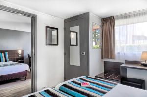 una camera d'albergo con letto e specchio di Sure Hotel by Best Western Biarritz Aeroport a Biarritz