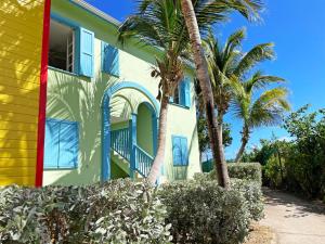 une maison colorée avec des palmiers devant elle dans l'établissement Orient Bay Beach Front Apartment, à La Baie-Orientale