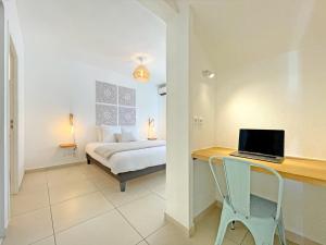 a bedroom with a bed and a desk with a laptop at Orient Bay Beach Front Apartment in Orient Bay