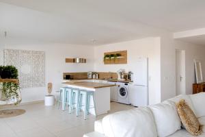 a white living room with a white couch and a kitchen at Orient Bay Beach Front Apartment in Orient Bay