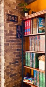 un estante de libros lleno de DVD junto a una pared de ladrillo en The First Nanwan Hostel, en Nanwan