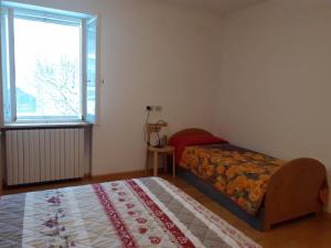 Schlafzimmer mit einem Bett, einem Fenster und einem Teppich in der Unterkunft Vacanzemoena - Casa al Parco, tipologia 2 in Moena