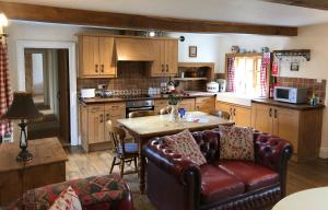 a kitchen with a leather couch and a table in it at Elm Tree Cottage in Salton